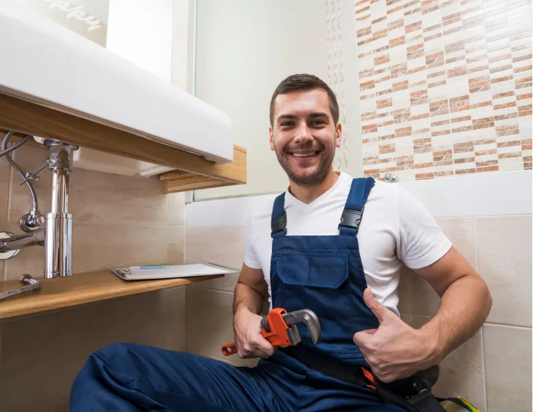 Smiling plumber holding a pipe wrench.