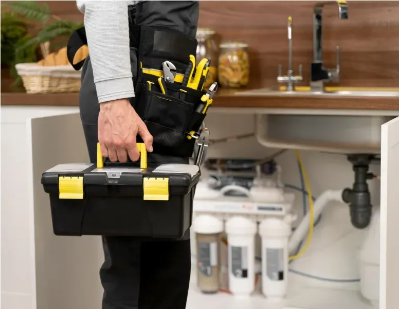 Plumber carrying toolbox in kitchen.